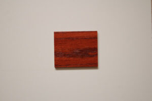 Red oak wood sample with a vibrant wild cherry stain, emphasizing the striking grain patterns and rich color depth, representative of C&S Cabinets' selection for luxurious custom cabinetry finishes.