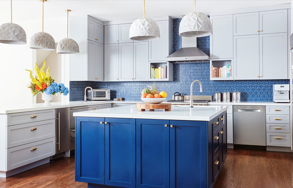 Elegant kitchen interior featuring two-toned cabinetry with classic grey upper cabinets and a vibrant blue island, accented by brass hardware and a geometric blue backsplash, embodying the custom craftsmanship of C&S Cabinets.